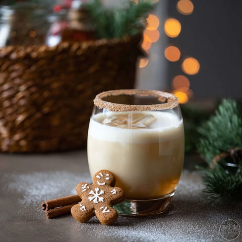A glass of white russian with a gingerbread cookie on the side.